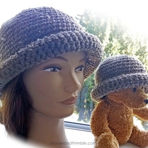 May include: Two crocheted hats, one gray and one brown, are shown on a mannequin and a teddy bear. The hats have a wide brim and a textured stitch.