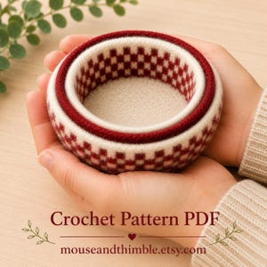 Può includere: Una piccola ciotola rotonda in feltro con un motivo a scacchi color crema e rosso scuro. La ciotola presenta un bordo spesso e testurizzato e una base interna color crema tinta unita. Il testo "Crochet Pattern PDF" e "mouseandthimble.etsy.com" è visibile.