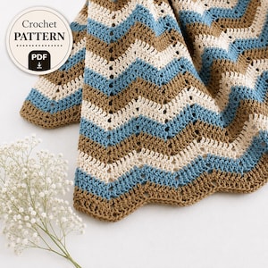 May include: A crochet pattern PDF featuring a chevron design in alternating stripes of blue, cream, and brown. The text on the circular badge reads Crochet PATTERN PDF. The blanket has a textured stitch pattern with a scalloped edge finish.