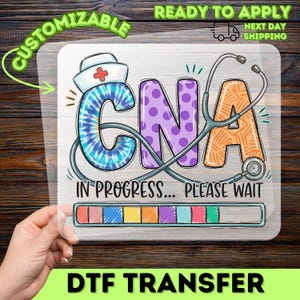 May include: A rectangular DTF transfer sheet featuring the text CNA in large, colorful letters. The C has a blue tie-dye pattern and a nurse cap, the N is purple with polka dots, and the A is orange with a stethoscope wrapped around it.