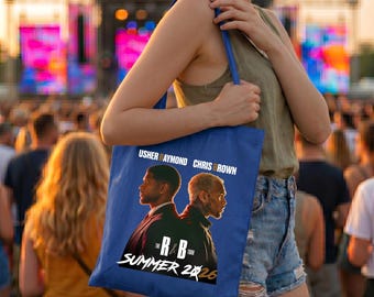 May include: Blue tote bag featuring Usher Raymond and Chris Brown with "The R&B Tour Summer 2026" text. The bag is carried by a person at an outdoor concert.
