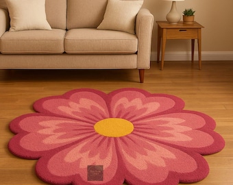 May include: A large, flower-shaped rug with a vibrant design. The rug features a bright yellow centre and petals in shades of pink and red. The rug is placed on a wooden floor in front of a beige sofa.