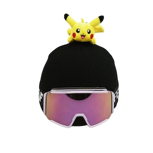 May include: A black knit beanie with a small Pikachu plush attached to the top. The beanie has a white band with black text. Pink and white ski goggles are positioned below the beanie.