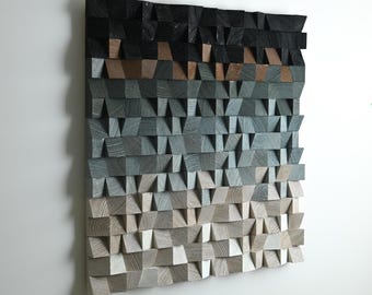 May include: A square wall art piece composed of numerous small, rectangular wooden blocks arranged in a grid. The blocks feature a gradient color scheme, transitioning from dark black at the top to light beige and white at the bottom.