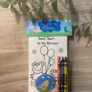 Peut inclure: Un ensemble de coloriage sur le th&egrave;me de l'anniversaire avec des personnages de Peppa Pig. L'ensemble comprend un livre de coloriage avec le texte "Snort Snort... It's My Birthday!!" et "Happy Birthday Olivia", trois crayons Crayola et un autocollant rond.