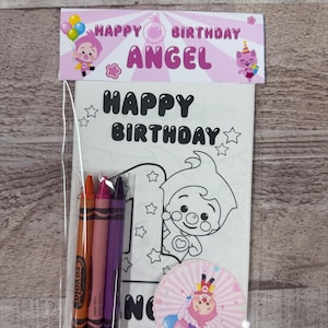 May include: A clear plastic bag contains a birthday-themed coloring set. The set includes a coloring page with a cartoon character, three crayons, and a decorative cupcake topper. The banner reads "Happy Birthday Angel".