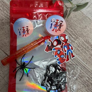 May include: A red cellophane bag filled with Spider-Man themed party favors. Includes stickers, a red pen, a black spider, and a circular sticker that says "Thank you for celebrating my birthday with me."