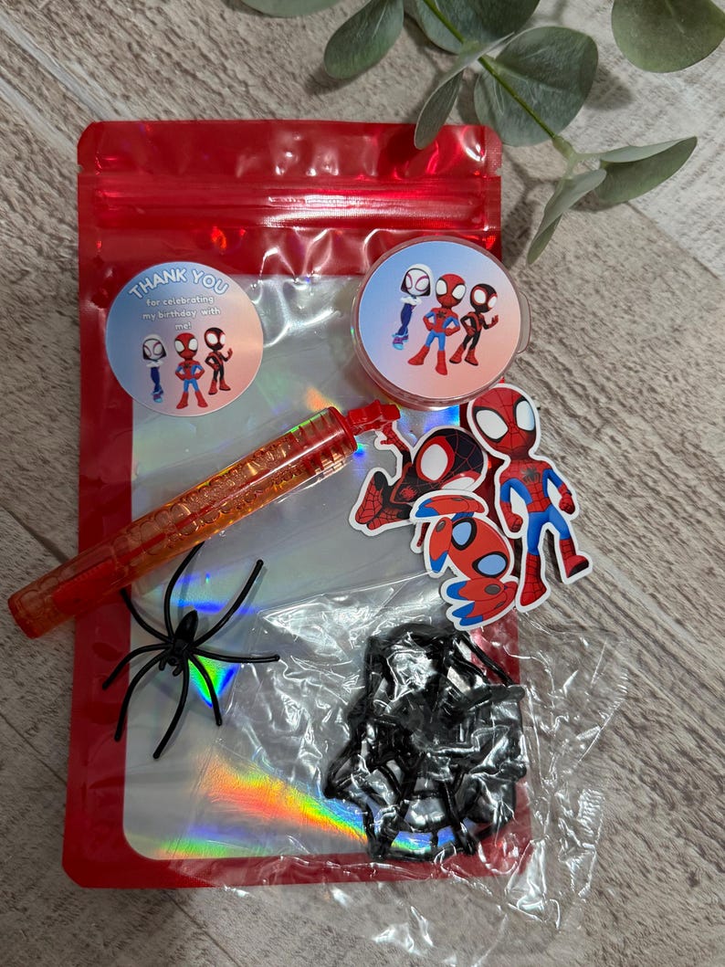 May include: A red cellophane bag filled with Spider-Man themed party favors. Includes stickers, a red pen, a black spider, and a circular sticker that says "Thank you for celebrating my birthday with me."