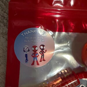 May include: A red plastic bag with a clear window, containing a bubble wand and a round sticker. The sticker says "Thank You for celebrating my birthday with me!" and features three cartoon Spider-Man characters.