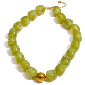 May include: A statement necklace with large, olive-green, rectangular beads with a marbled effect. The necklace has a gold-coloured metal clasp and a large, round, gold-coloured bead as a focal point. The necklace is a bold accessory.