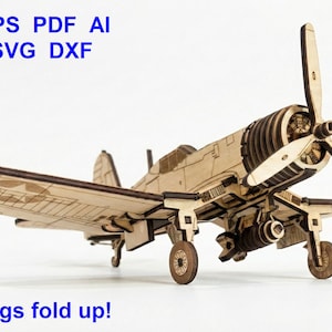 Puede incluir: Un modelo de avión de madera cortado con láser con una hélice de tres palas, tren de aterrizaje y alas que se pliegan. El texto CDR EPS PDF AI LBRN SVG DXF aparece en la esquina superior izquierda y The wings fold up! en la parte inferior.