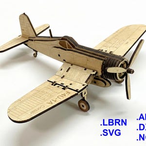 Puede incluir: Maqueta de madera de un avión F4U-1A Corsair. El modelo está hecho de madera clara con detalles más oscuros, incluyendo una hélice, alas y cola. El texto "F4U-1A Corsair" es visible en el ala. También se muestran extensiones de tipo de archivo.