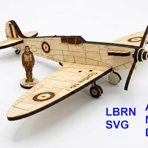Könnte beinhalten: Ein Holzmodell eines Spitfire Mk I-Flugzeugs mit einer Pilotenfigur. Das Modell ist hellbraun mit dunkelbraunen Akzenten und verfügt über einen Propeller, Flügel und Fahrwerk. Der Text "Spitfire Mk I" ist auf dem Flügel zu sehen.