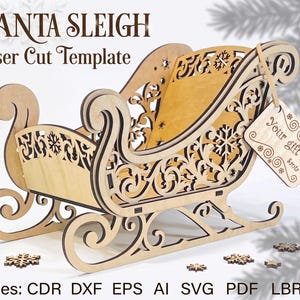 Puede incluir: Una plantilla de trineo de Santa Claus cortada con láser en madera clara con intrincados patrones de volutas y copos de nieve. Una pequeña etiqueta de madera cuelga del lateral con el texto "Your gift!" y "Sants". El texto superior dice "SANTA SLEIGH Laser Cut Template" y el inferior "Files: CDR DXF EPS AI SVG PDF LBRN".