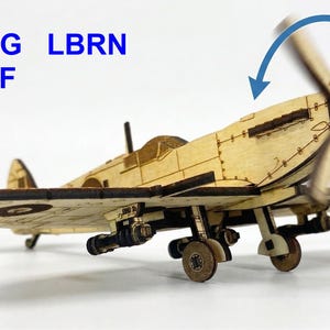 May include: A wooden model airplane with a spinning propeller and a small pilot figure. The model is light brown with dark brown accents. The text "AI SVG LBRN NC DXF" is in the upper left corner.
