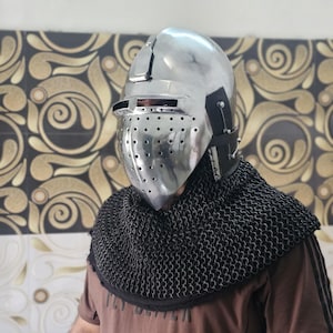 Puede incluir: Un casco medieval plateado brillante con una placa frontal perforada y una visera. Se combina con una cofia de cota de malla negra. El diseño está inspirado en la armadura histórica, adecuado para cosplay o recreaciones históricas.