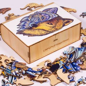 May include: A wooden box with a colorful wolf illustration on the lid. The box is open and the pieces of a jigsaw puzzle are scattered around it. The box is labeled "LINPOPUP MagicWood".