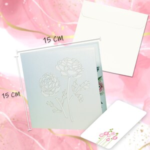 May include: A light blue greeting card with a floral design, measuring 15 cm x 15 cm, accompanied by a white envelope and a smaller card with pink flower illustrations. The card features a cut-out of two flowers.