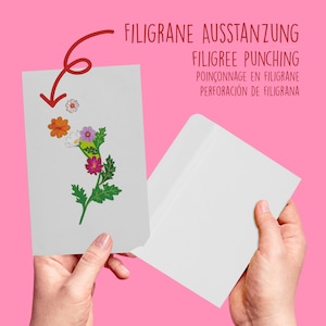 Peut inclure: Une carte blanche avec un motif floral sur le devant. La carte est tenue dans une main et est plac&eacute;e dans une enveloppe blanche. Le texte sur l'enveloppe est "FILIGRANE AUSSTANZUNG FILIGREE PUNCHING POIN&Ccedil;ONNAGE EN FILIGRANE PERFORACI&Oacute;N DE FILIGRANA".