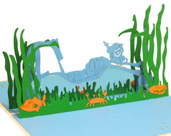 May include: A blue scuba diver with a green diving mask and snorkel is swimming through a green seaweed forest. There are two orange crabs and an orange fish in the scene.
