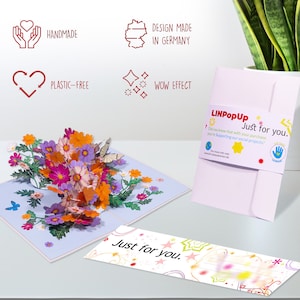 Peut inclure: Une carte pop-up 3D avec un bouquet de fleurs color&eacute;es. La carte est ouverte et les fleurs sortent. La carte est sur une surface blanche. La carte a un message qui dit "Just for you." La carte est fabriqu&eacute;e par LINPopUp et soutient des projets sociaux.