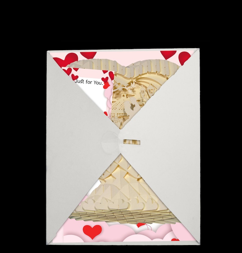 Peut inclure: Une enveloppe blanche contenant une carte en forme de c&oelig;ur rose et blanche. La carte pr&eacute;sente un design en papier d&eacute;coup&eacute; en 3D d'un c&oelig;ur avec un nichoir &agrave; oiseaux et des fleurs. La carte porte le texte "Just for You." imprim&eacute; dessus.
