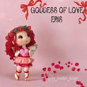 May include: A handmade crochet doll with red hair, a pink dress, and angel wings. The doll holds a pink heart and is adorned with a rose crown. The text "Goddess of Love Eris" is above the doll on a pink background.