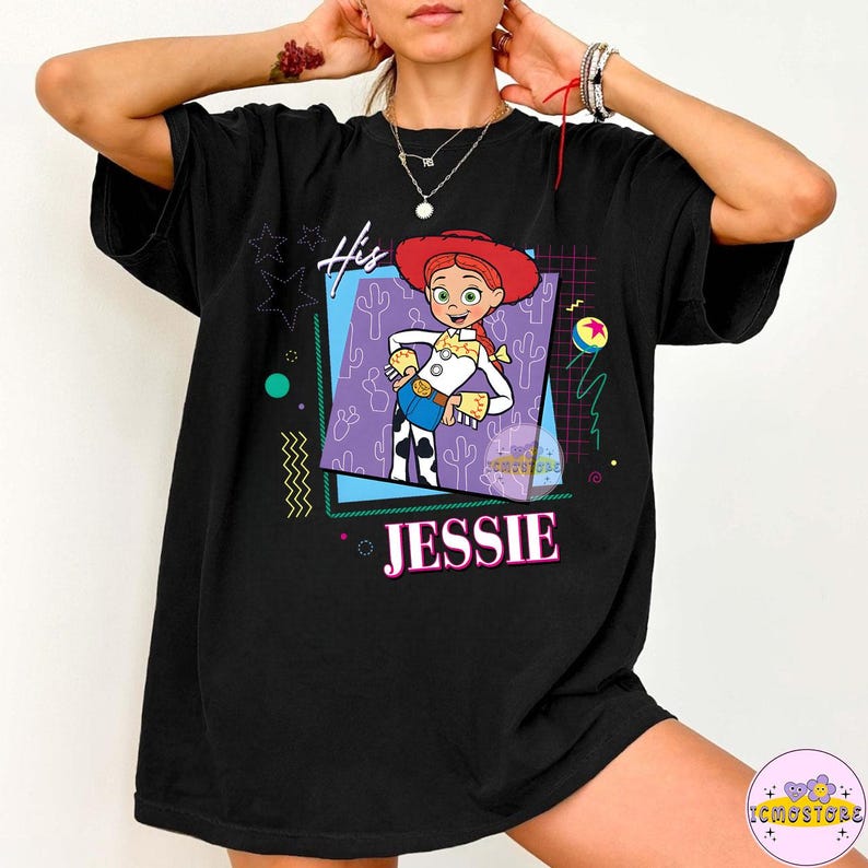 May include: Black t-shirt featuring a graphic of Jessie from Toy Story. The design includes the text "His" and "Jessie" in pink, with a cartoon image of the character in a square frame. The shirt has a relaxed fit.