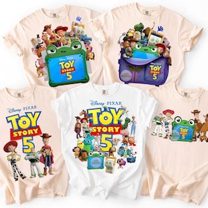 Può includere: Cinque magliette con disegni del film Disney Pixar Toy Story 5. Le magliette sono in vari colori, tra cui bianco e beige, e presentano personaggi come Woody e Buzz Lightyear. Il testo "TOY STORY 5" è ben visibile.