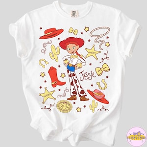 May include: White t-shirt featuring a cartoon illustration of Jessie from Toy Story. The design includes a red hat, sheriff star, cactus, and the name "Jessie". The shirt has a crew neck and short sleeves.