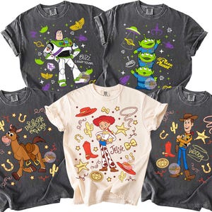May include: Five graphic t-shirts featuring characters from the Toy Story franchise. Designs include Buzz Lightyear, the Pizza Planet aliens, Jessie, Bullseye, and Woody. The shirts are in various colors, including black and cream.