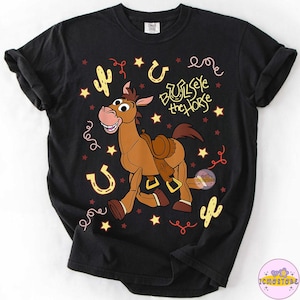 May include: Black t-shirt featuring a cartoon image of Bullseye the horse from Toy Story. The design includes stars, horseshoes, and cacti. The text "Bullseye the Horse" is also printed on the shirt.