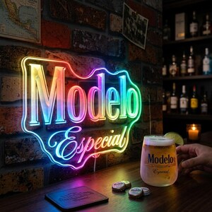 Könnte beinhalten: Ein Neon-Schild mit der Aufschrift "Modelo Especial" in einem bunten Farbverlauf, an einer Backsteinmauer. Ein Bierglas mit Limettenscheibe steht auf einer Holzbar, dazu Flaschendeckel und ein Untersetzer.