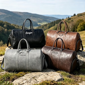 May include: Four duffel bags in black, brown, tan, and gray, each featuring a textured surface, dual top handles, and a detachable shoulder strap. The bags are personalized with names like Sawyer and Lucas or a letter G with antler graphics.