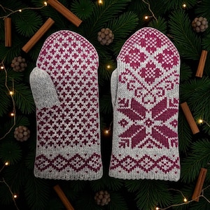 Op de afbeelding: Een paar grijs en bordeaux gebreide wanten. De wanten hebben geometrische patronen in bordeaux op een grijze achtergrond. Het ontwerp bevat diamant- en sneeuwvlokmotieven. De wanten worden getoond op een achtergrond van dennennaalden, kaneelstokjes en kleine dennenappels.