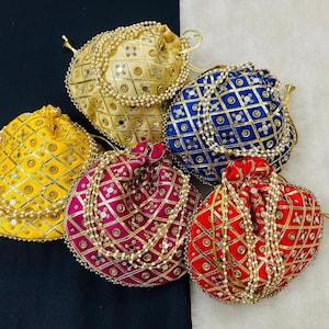 May include: An assortment of five colorful, embroidered drawstring pouches. The pouches are in shades of yellow, gold, blue, red, and pink, with intricate patterns and beaded accents. Each pouch has a drawstring closure.