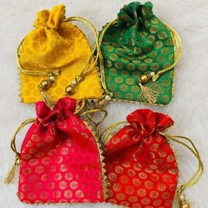 May include: Four colourful drawstring pouches in yellow, green, and two shades of red. Each pouch features a gold floral pattern, gold trim, and a gold drawstring with decorative tassels. These pouches are suitable for small gifts or jewellery.