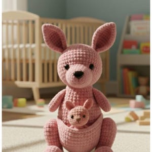 May include: A pink crochet kangaroo with a baby kangaroo in its pouch. The kangaroo has large ears and a black nose. The text "Crochet pattern PDF" is at the top of the image. A "PDF Download" button is in the lower right corner.