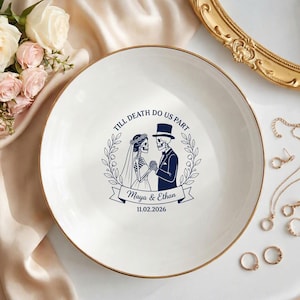 Op de afbeelding: Een wit keramieken bord met een gouden rand, voorzien van een donkerblauwe afbeelding van twee skeletten in trouwkleding, een bloemenkrans en de tekst "TILL DEATH DO US PART", "Maya & Ethan" en de datum "11.02.2026" in het midden.