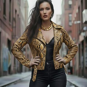 May include: A yellow and brown snakeskin-patterned leather jacket with a zipper closure. The jacket is paired with a black top, black jeans, and a gold chain necklace. The model is standing in an alleyway.