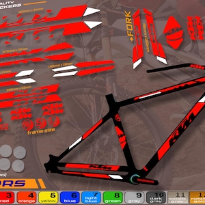 Op de afbeelding: Fietsstickers in rood, wit en zwart, met de tekst "KTM" en diverse grafische ontwerpen. Inclusief stickers voor het frame, de vork en andere onderdelen, met een kleurenschema.