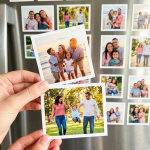 May include: A collection of family photos displayed on a refrigerator. The photos are square and feature various families in outdoor settings. Two photos are held in a hand, showing a family at the beach and another in a park.