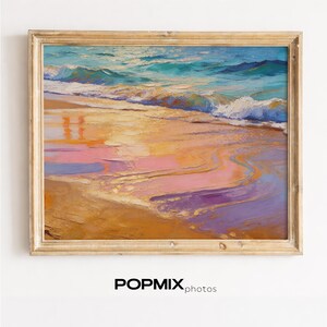 Puede incluir: Pintura al óleo enmarcada en oro que representa una escena de playa. La obra muestra olas en tonos azules y turquesas rompiendo en una orilla arenosa con tonos naranja, rosa y morado. El texto "POPMIX photos" está en la parte inferior.