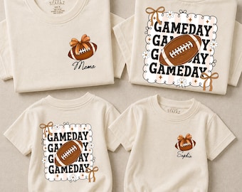 May include: Four cream-colored shirts and bodysuits featuring football-themed graphics. Two garments display a football with a bow and the text Mama or Sophia, while two feature a repeating GAMEDAY text, a football, and floral accents.