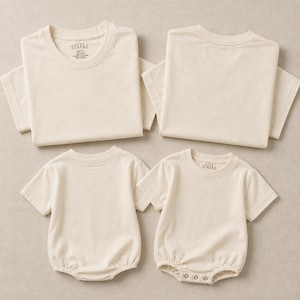 May include: Two cream-colored short-sleeve t-shirts and two cream-colored short-sleeve baby rompers. The t-shirts feature a printed label inside the neck reading STAFAZ, size M, 100% cotton, made in Vietnam. The rompers have a snap-button closure.