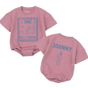 May include: A dusty rose short-sleeved romper featuring a blue graphic print on the front with a goose, party elements, and the text ONE SILLY GOOSE. The back displays the name JOHNNY in blue letters above a blue graphic of a number one candle.