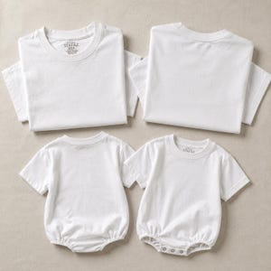 May include: Two plain white short-sleeved t-shirts and two plain white short-sleeved baby bodysuits with snap closures at the bottom. Each garment features a round neckline and the Stafaz brand label printed on the inside of the collar area.