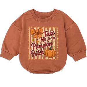 May include: A rust-colored long-sleeve sweatshirt romper with a ribbed crew neckline and cuffs. The center features a graphic with a large orange bow, a pumpkin, and the text "Take Me to the Pumpkin Patch" set against a striped background.