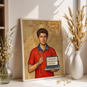Könnte beinhalten: Gerahmtes Kunstwerk mit einem jungen Mann in einem roten Poloshirt, der ein Kreuz und einen Laptop hält. Das Kunstwerk hat einen Heiligenschein und Text in Griechisch und Italienisch. Das Bild wird auf einer weißen Oberfläche mit Vasen mit Blumen und Weizen gezeigt.