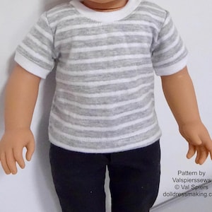 Pode incluir: Uma camiseta listrada cinza e branca com acabamento branco na gola e mangas. A camiseta é usada por uma boneca e é combinada com calças pretas. Padrão de Valspierressews © Val Spiers dolldressmaking.com